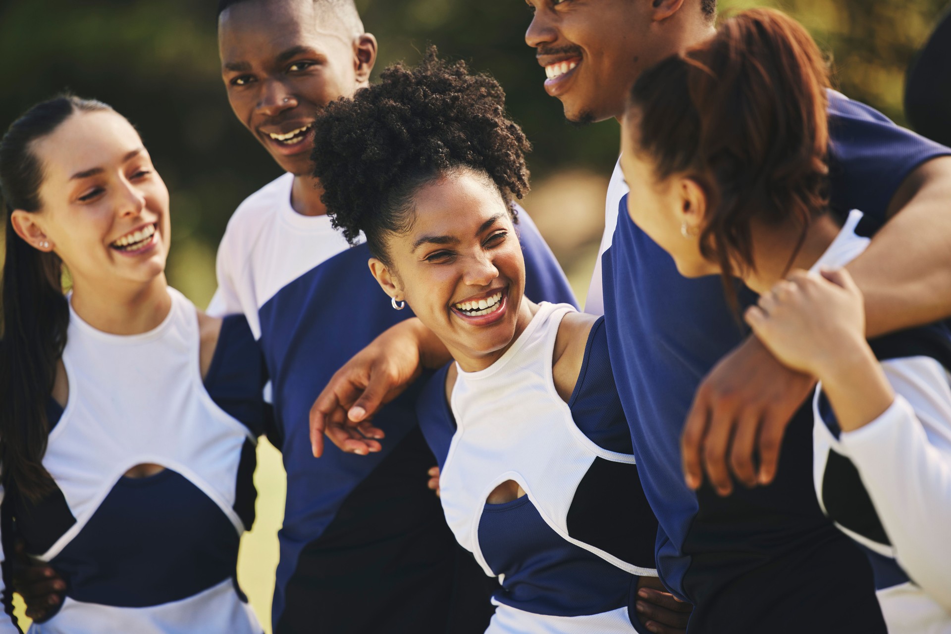 Sports team, hug or happy cheerleaders with support outdoor training or event and game together on field. Diversity people, smile or proud friends or excited squad, winning celebration and fitness